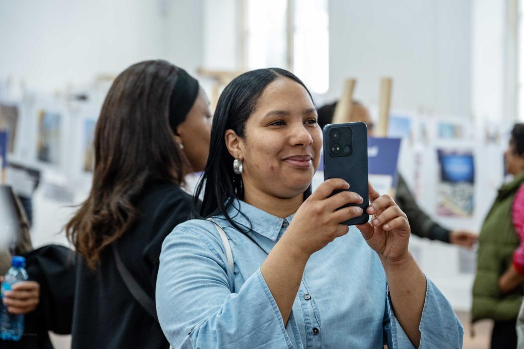 person in exhibition space smiling and taking pictures with mobile phone