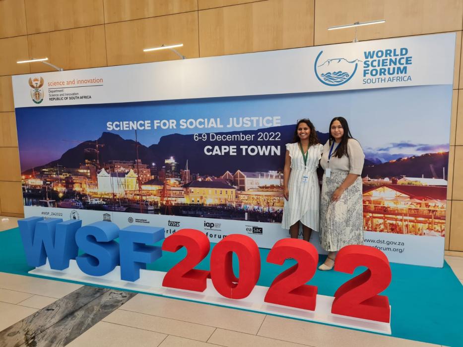 Nadine Veldsman and Imaan Mohamed standing in front of the World Science Forum signage