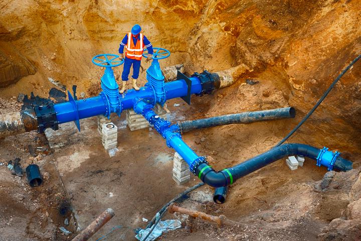Technical expert underground at gate valve on 500mm drink water pipes joined with new black waga multi joint members into old pipeline system. Stock image