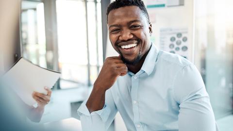 Portrait of male person smiling, in seminar room with team