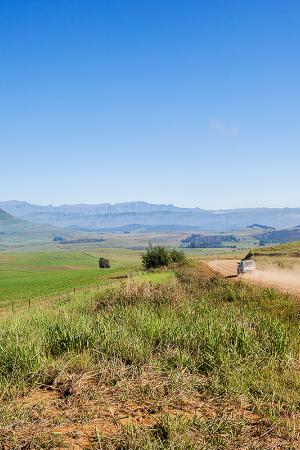 Landscape overlooking rural farmlands mountain with vehicle on dirt road terrain