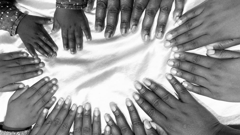 Many hands from toddler to adult coming together, fingers touching