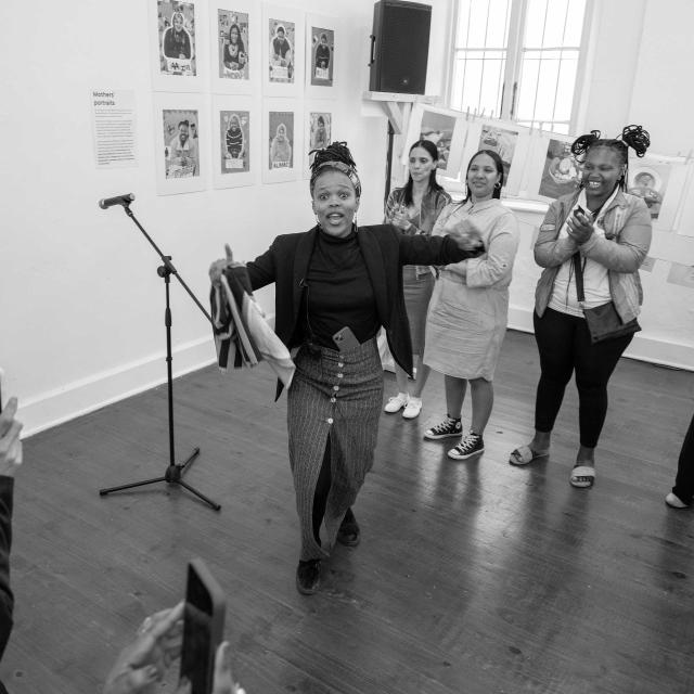 one person dancing, group of four people in background clapping and smiling