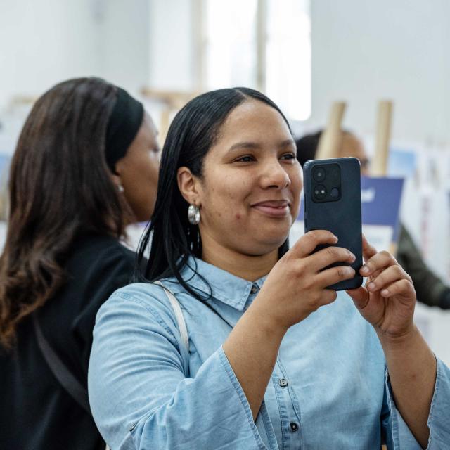 person in exhibition space smiling and taking pictures with mobile phone