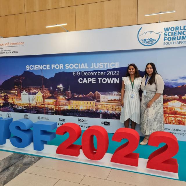 Nadine Veldsman and Imaan Mohamed standing in front of the World Science Forum signage