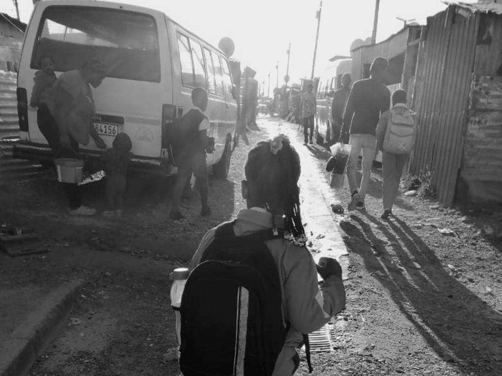 Black and white picture – a street in township with parents and school kids walking at sunrise