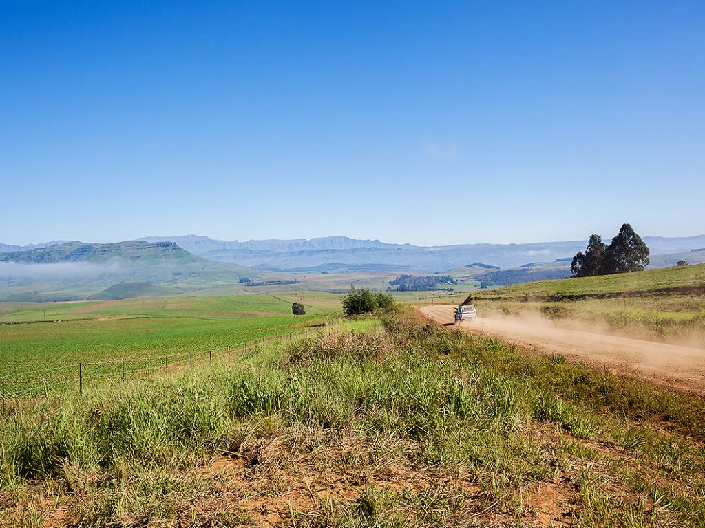 Landscape overlooking rural farmlands mountain with vehicle on dirt road terrain