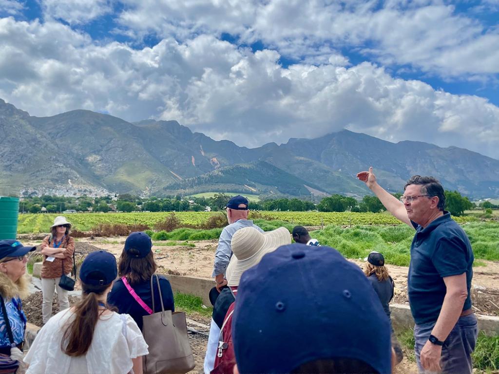 Group of people standing in green field, mountains in the background