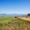 Landscape overlooking rural farmlands mountain with vehicle on dirt road terrain