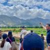 Group of people standing in green field, mountains in the background