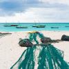 Large fishing nets lying on african beach with boats near the shore